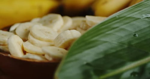 Banana Slices in Bowl Next to Tropical Leaf