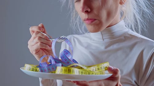 Woman eating measuring tapes with fork