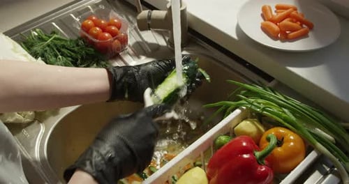 Cucumber Being Washed By a Person Wearing Gloves
