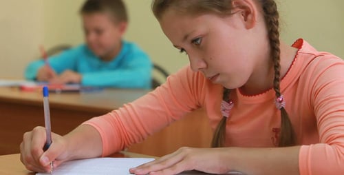 Girl Studying and Writing at Her School Desk