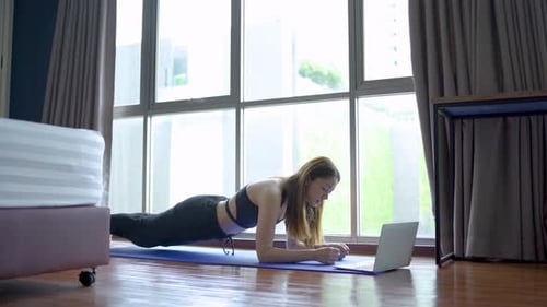 Woman Exercising Doing Plank at Home with Laptop