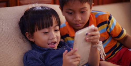 Girl and Boy Using Tablet on Couch
