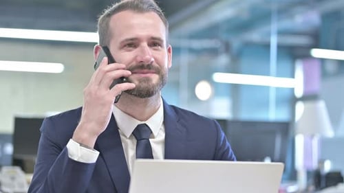 Portrait of Businessman Talking on Smartphone in Office