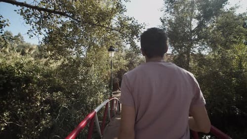 YOUNG CONFIDENT MEN WALKING THROUGH JUNGLE FOREST OVER BRIDGE IN MOROCCO ON SUNNY DAY