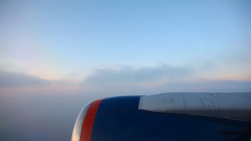 Airplane Window View Flying Over Clouds at Sunset