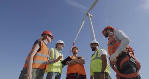 Colleagues Discussing Windmill on Wind Farm