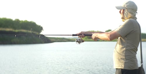 Man Casting Fishing Rod Into Tranquil Lake