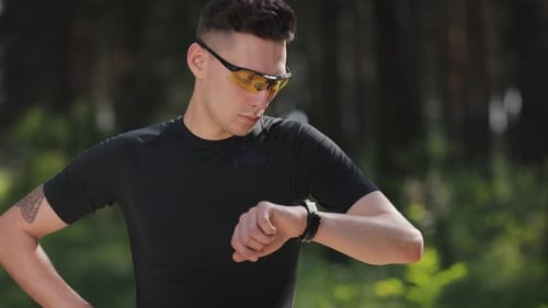 Man Checks Smart Watch in Wooded Setting