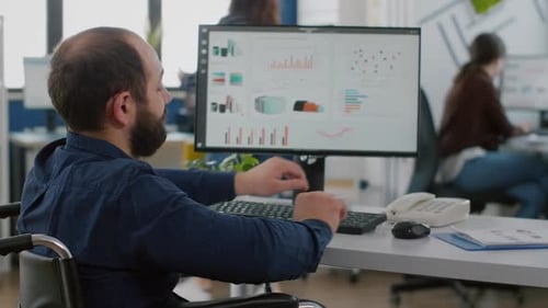 Man in Wheelchair Working at Computer in Office