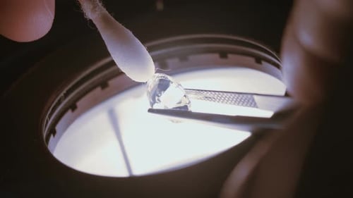 A gemologist inspecting a large clear diamond under a microscope
