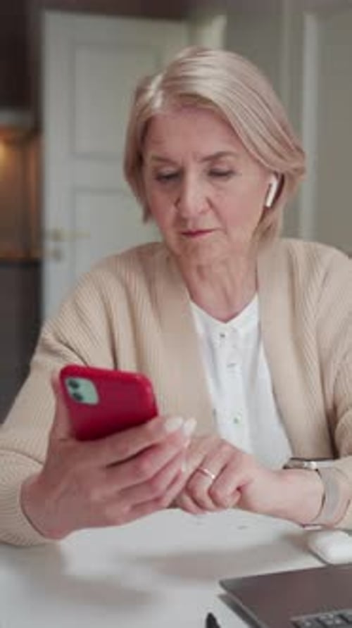 An Elderly Woman Sits Near a Laptop