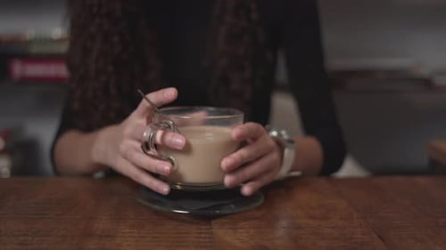 Woman Drinks Latte at a Table Indoors