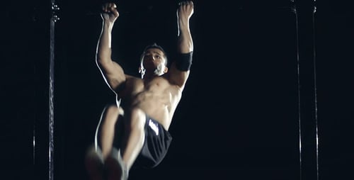 Male Athlete Performing Gymnastics on Horizontal Bar at Night