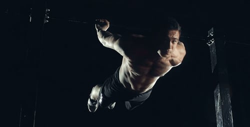 Strong Man Doing Gymnastics on Pull-up Bar at Night