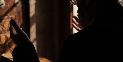 Man Praying with Religious Book by Ornate Window