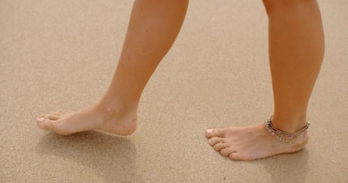 Close Up Of Woman Walking On Sandy Beach