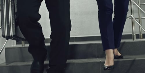 Man and Woman Walking Down Steps With Briefcase