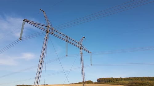 Electricity Pylons in Rural Field under Blue Sky
