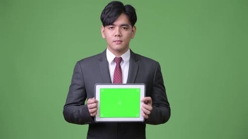 Young Adult Holds Tablet With Green Screen