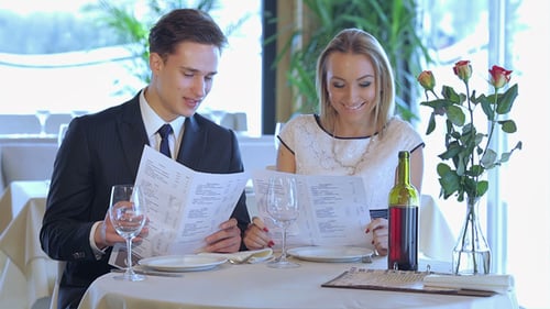 Couple Reviews Menus at Restaurant Table