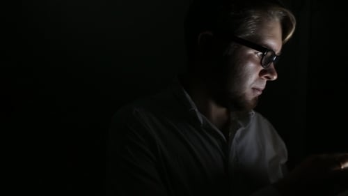 Man Using Tablet in Dark Room at Night