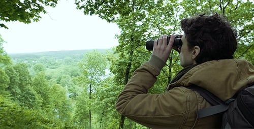 Hiker Observes Expansive Landscape Through Binoculars