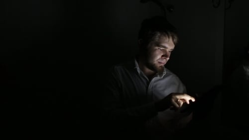 Man Uses Tablet in Dark, Intimate Setting