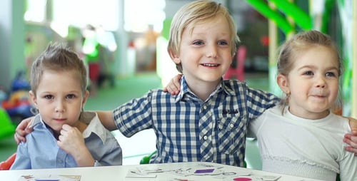 Happy Children Smile at Table in Play Area