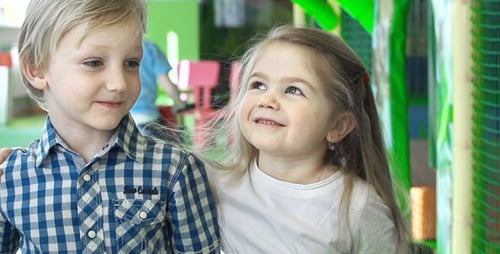 Smiling Boy and Girl Hugging in Playroom