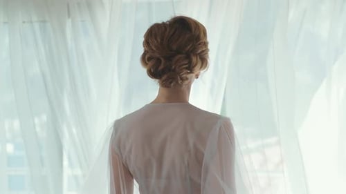 Back of Bride in White Robe by Window