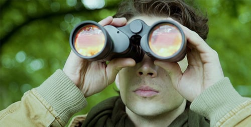Man Looks Through Binoculars in Forest