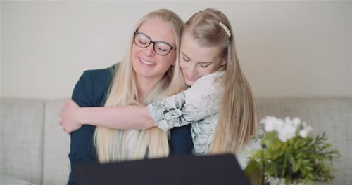 Two Women Hugging on Couch Indoors