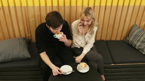 Young Cheerful Woman Talking Via Cell Phone, While Dating in the Coffee Shop