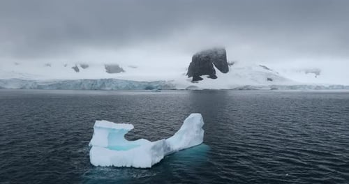 WS Eisberg und schneebedeckte Küste von Cuverville Island an bewölktem Tag/Antarktis