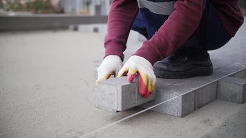 footage of builder lays paving slabs