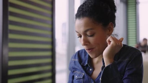 Young Happy African American Woman Enjoying Aromatic Coffee and Chocolate Sitting at Tables in Cafe