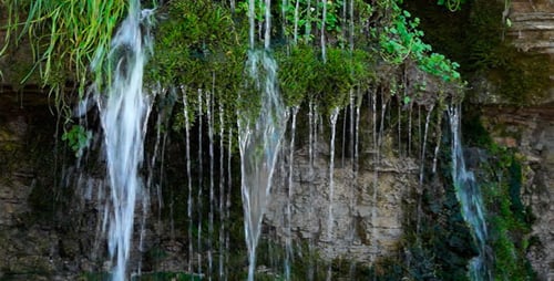 Tranquil Waterfall Flowing Over Mossy Rocks