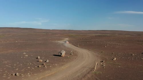 Car Drives Through Remote, Dusty Desert Landscape