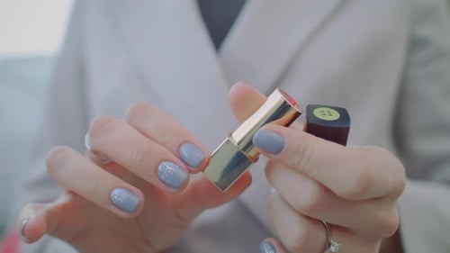 Woman's Hands Holding Gold and Red Lipstick
