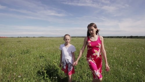 Sisters Walking Hand in Hand Through a Grassy Field