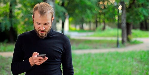 Bearded Man Using Phone in Park Setting