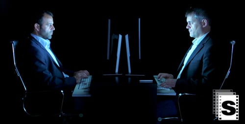 Men Typing At Desks In Dark Room