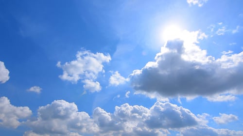 Blue Sky With Fluffy White Clouds and Sun