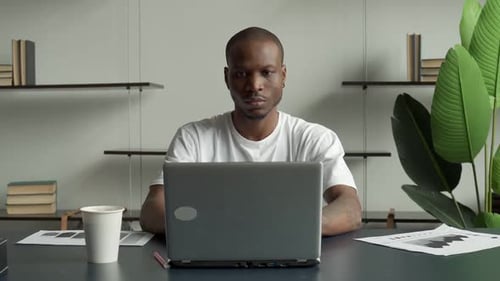 Man Smiling in Front of Laptop at Desk