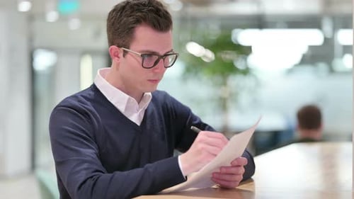 Young Man Writing on Document Indoors