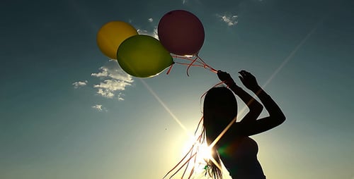 Young Woman Silhouette with Balloons at Sunset