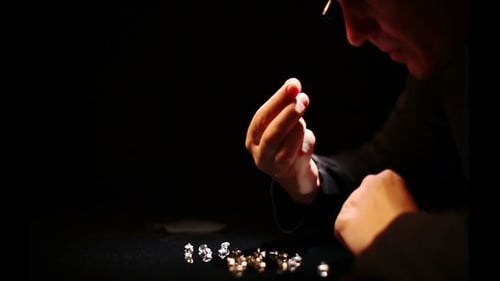 Person Inspecting Diamonds with Tweezers and Magnifying Glass