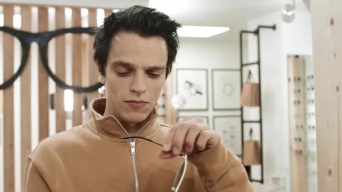 Young Man Choosing Sunglasses in Optician Store