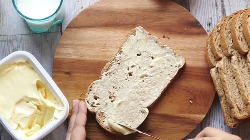 Hands Spreading Butter on Bread Slice for Breakfast