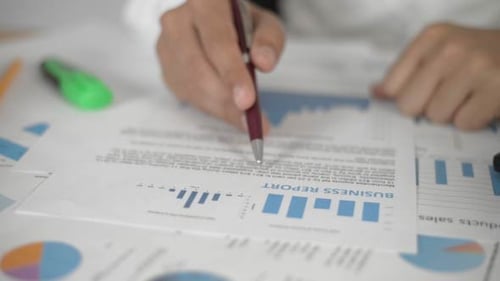 Hands Reviewing Business Report with Pen in Office